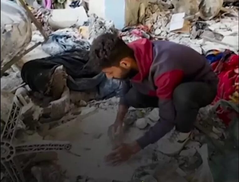 A displaced Palestinian refugee gathers flour amidst the rubble